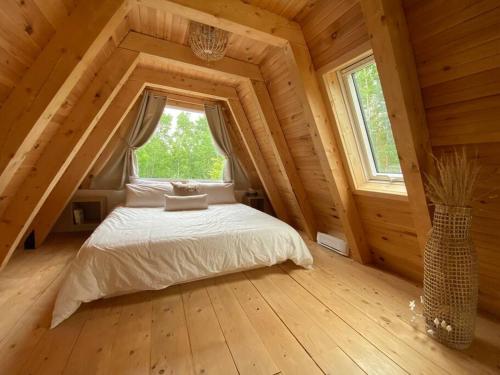 ein Schlafzimmer in einem Blockhaus mit einem Bett und einem Fenster in der Unterkunft Chapella A Frame in LʼAnse-Saint-Jean