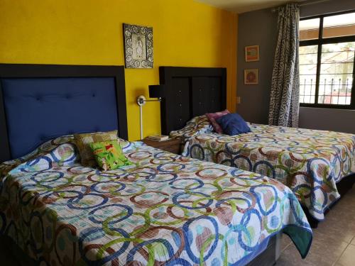 2 Betten in einem Zimmer mit gelben Wänden in der Unterkunft Casa de campo en Teziutlán, Puebla. in Teziutlán