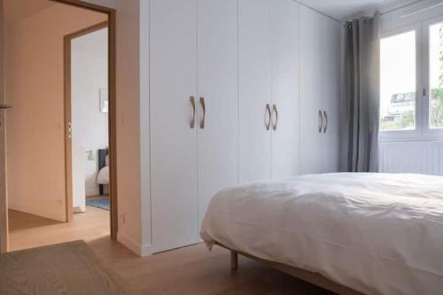 une chambre blanche avec un lit et un miroir dans l'établissement Le QUAI Paris-Boulogne-île Saint Germain au calme avec parking, à Boulogne-Billancourt