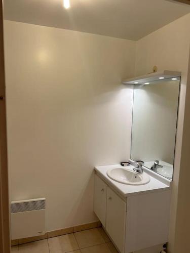 une salle de bain blanche avec un lavabo et un miroir dans l'établissement Studio à 2 pas du métro, à Clichy