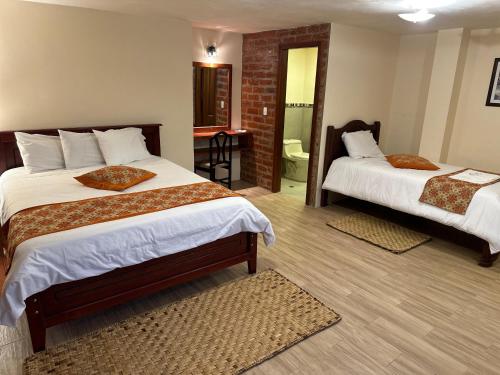 a bedroom with two beds and a bathroom at Spa Hotel Etelvina in Quillullaco