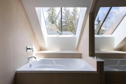 a bathroom with a large tub and two windows at Stylish Home with Mountain Views by Harmony Whistler in Whistler