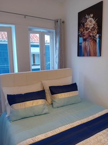 a bed in a room with two windows at Chalas bedroom in Nazaré