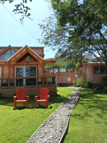 uma casa com duas cadeiras vermelhas no quintal em Buenavida Guesthouse em Ushuaia