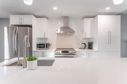 una cocina blanca con armarios blancos y electrodomésticos de acero inoxidable en Modern Downtown 3BR 2B Home, en Yellowknife
