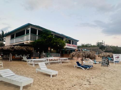 a group of chairs and tables on a beach at Tamboo Resort in Negril