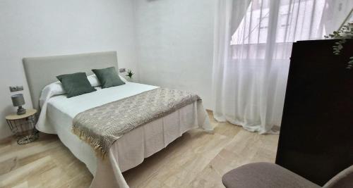een slaapkamer met een wit bed met groene kussens en een raam bij Azahar home in Córdoba