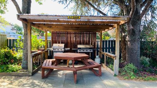 a wooden gazebo with a picnic table and a grill at Alpha Motor Inn in Palmerston North