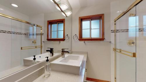 a white bathroom with a sink and a shower at PRIVATE Hot Tub In Prestigious Nicklaus North by Harmony Whistler in Whistler