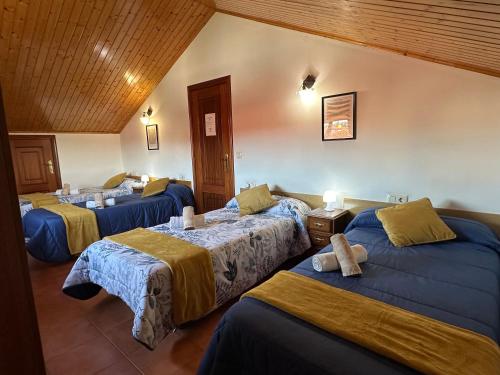 um quarto de hotel com três camas num quarto em Pensión Codesal em O Pedrouzo