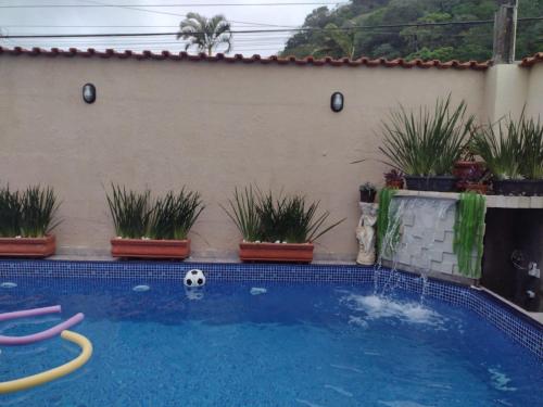 une piscine avec un ballon de football et des plantes en pot dans l'établissement Kazapraia, à Mongaguá