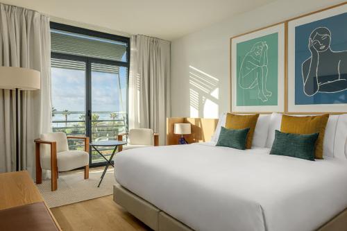 a bedroom with a large white bed and a balcony at AC Hotel Gava Mar in Gavà