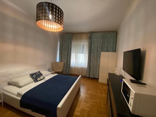 a bedroom with a bed and a television and a chandelier at Monolit Budapest Center Guesthouse in Budapest