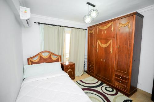 a bedroom with a bed and a large wooden cabinet at Cozy apartment New Cairo in New cairo