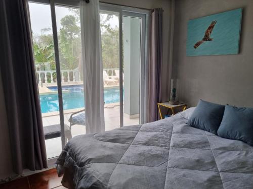 een slaapkamer met een bed en een raam met een zwembad bij Villa Helena in Los Altos de Cerro Azul