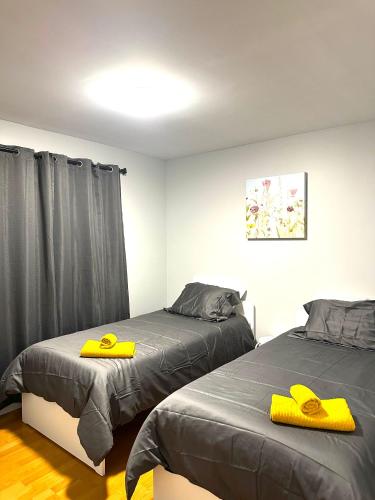 2 Betten in einem Schlafzimmer mit gelben Handtüchern darauf in der Unterkunft Spacious Downtown 3BR Home, 4bds in Yellowknife