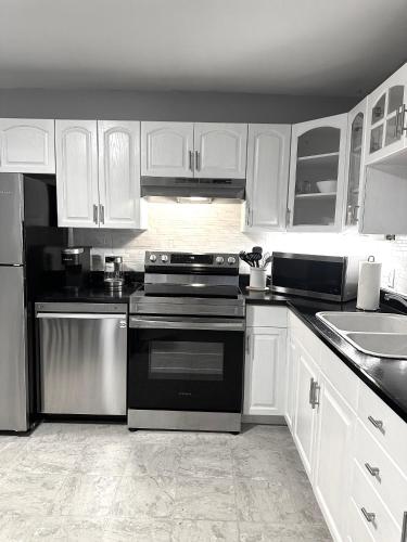 a kitchen with white cabinets and black appliances at Spacious Downtown 3BR Home, 4bds in Yellowknife