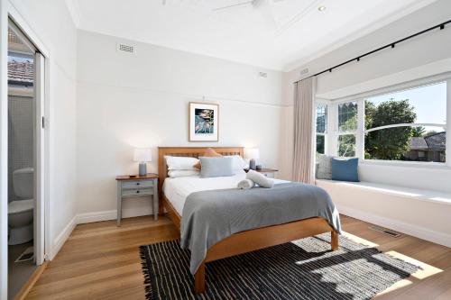 a white bedroom with a bed and a window at Essendon Allambee Haven 4BR in Melbourne