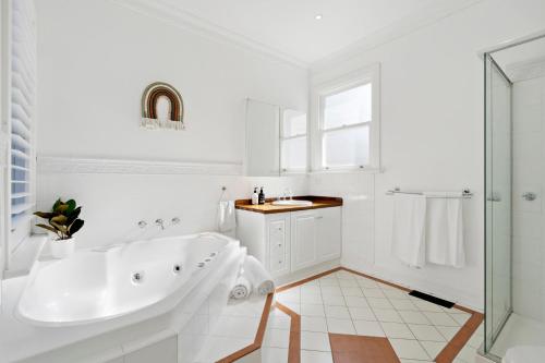 Baño blanco con bañera y lavamanos en Essendon Allambee Haven 4BR en Melbourne