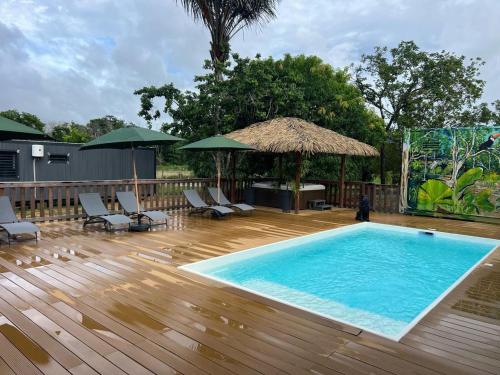 una piscina su una terrazza in legno con sedie e ombrelloni di MBS Studio LA CARAPA a Guenouillet