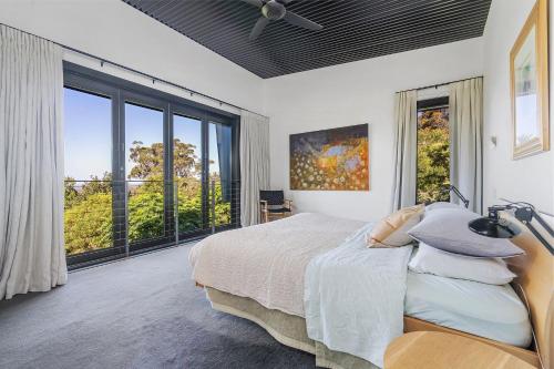 1 dormitorio con cama y ventana grande en Sanctuaire, Southern Highlands, en Mittagong
