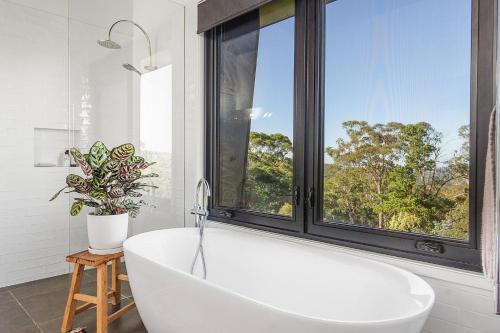 baño con bañera blanca y ventana en Sanctuaire, Southern Highlands, en Mittagong