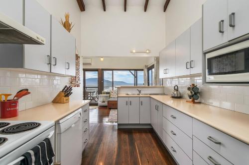 a kitchen with white cabinets and a stove top oven at Barrels Beach House, 28 Dulconghi Street in Crescent Head