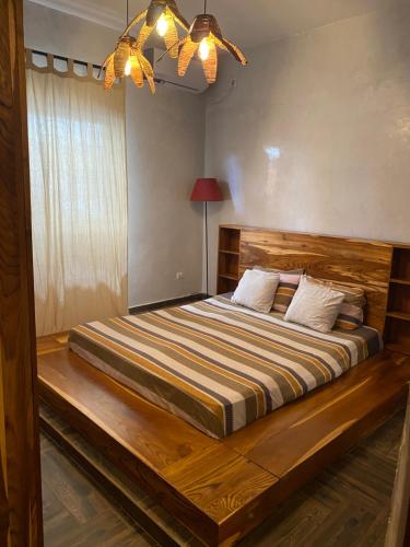 - une chambre avec un grand lit et une tête de lit en bois dans l'établissement Keur royal, à Dakar