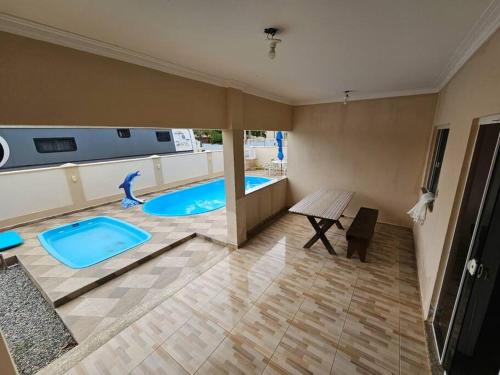 AraquariにあるCasa de praia com piscina TOPの2つのスイミングプールとテーブルが備わる広い客室です。