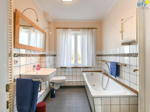 ein Badezimmer mit einer Badewanne, einem WC und einem Waschbecken in der Unterkunft Haus Skagen Ferienhaus Skagen Wangerooge in Wangerooge
