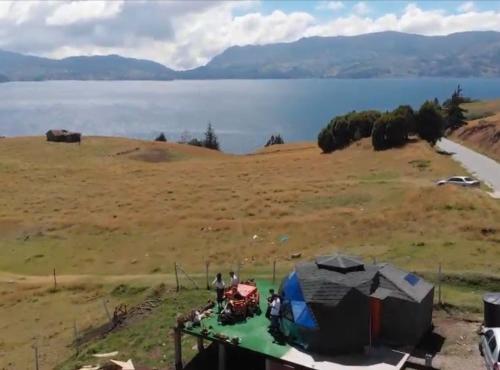 a group of tents on a field next to a lake at Villa San Jerónimo in Tota