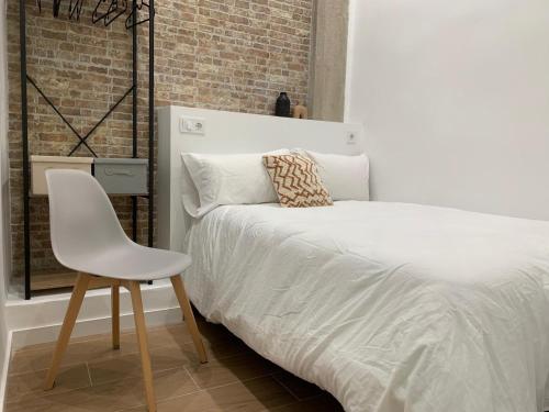 um quarto com uma cama branca e uma cadeira branca em Valencia beach rooms em Valência