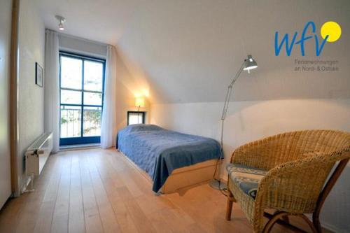 a bedroom with a bed and a lamp and a chair at Ferienhaus Friesenblick Ferienwohnung 2 in Wangerooge