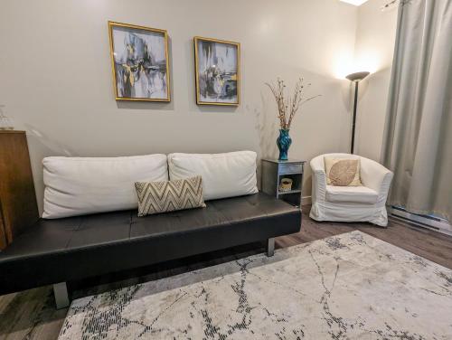 a living room with a black couch and a chair at Maple Rise Guesthouse in Duncan