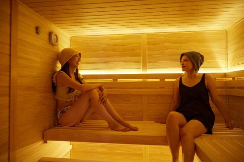two women sitting on a bed in a sauna at Rembrandt Atsugi BETTEI サウナ&無煙ロースター付き12名定員 in Atsugi
