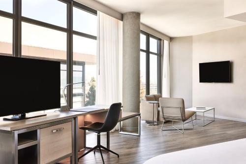 a living room with a flat screen tv and chairs at AC Hotel by Marriott Sunnyvale Moffett Park in Sunnyvale