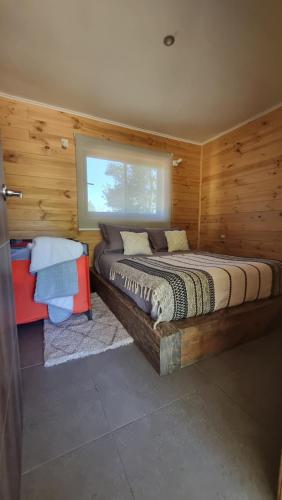 1 dormitorio con 1 cama grande en una habitación con paredes de madera en Peumayenlodge, en Antuco