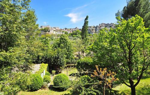 a garden with trees and buildings in the background at Les Lauriandes in Les Baux-de-Provence