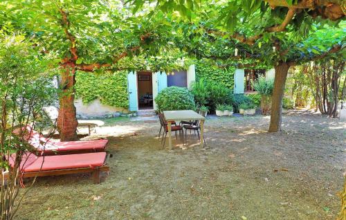 a patio with a table and chairs under a tree at Les Lauriandes in Les Baux-de-Provence