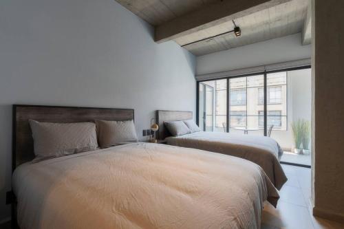 een slaapkamer met 2 bedden en een groot raam bij P302 Zocalo 3bdrm 2bath Rooftop AC in Mexico-Stad