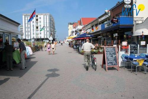 a man riding a bike down a city street at Ferienhaus Seeblick Ferienwohnung 65 in Borkum