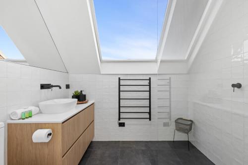 een badkamer met een wastafel en een dakraam bij Elegant & Stylish Home by the Botanical Gardens in Melbourne