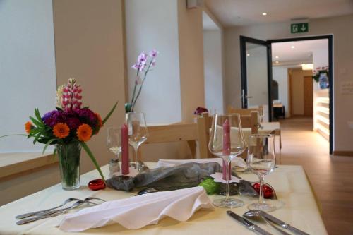 a table with glasses and a vase of flowers on it at Hotel Helvetia in Müstair