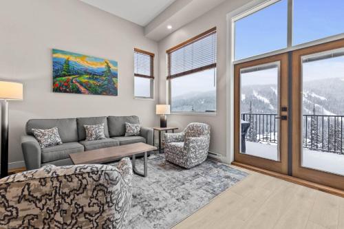 a living room with a couch and chairs and windows at Powder Heights #21 townhouse in Sun Peaks