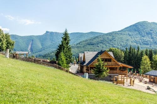 a log cabin on a hill with mountains in the background at Salaš Kľak in Fačkov