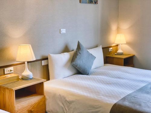 a bedroom with a bed and two lamps on tables at Loju Seaview Homestay in Xiaoliuqiu