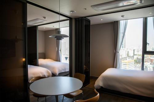 a hotel room with two beds and a table and a window at WECO STAY Namsan in Seoul