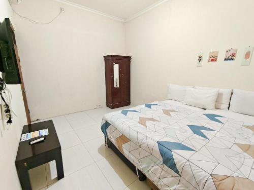 a bedroom with a bed and a nightstand with a table at Homey Guesthouse near Sby Zoo Syariah in Surabaya