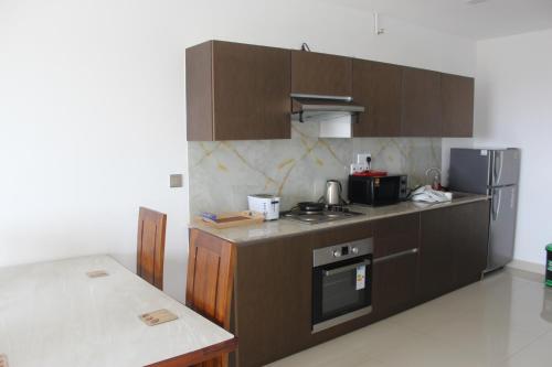 a kitchen with brown cabinets and a stove and refrigerator at Airport Luxury Ocean Condos in Negombo