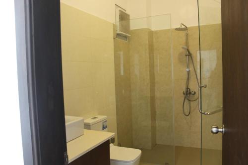 ein Bad mit einer Glasdusche und einem WC in der Unterkunft Luxury Ocean Condos by Travel Bee in Negombo